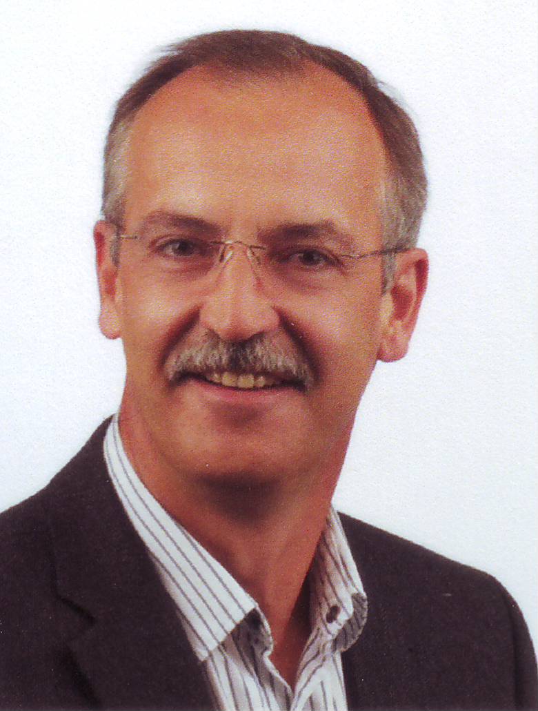 Un uomo con gli occhiali e i baffi sorride alla telecamera