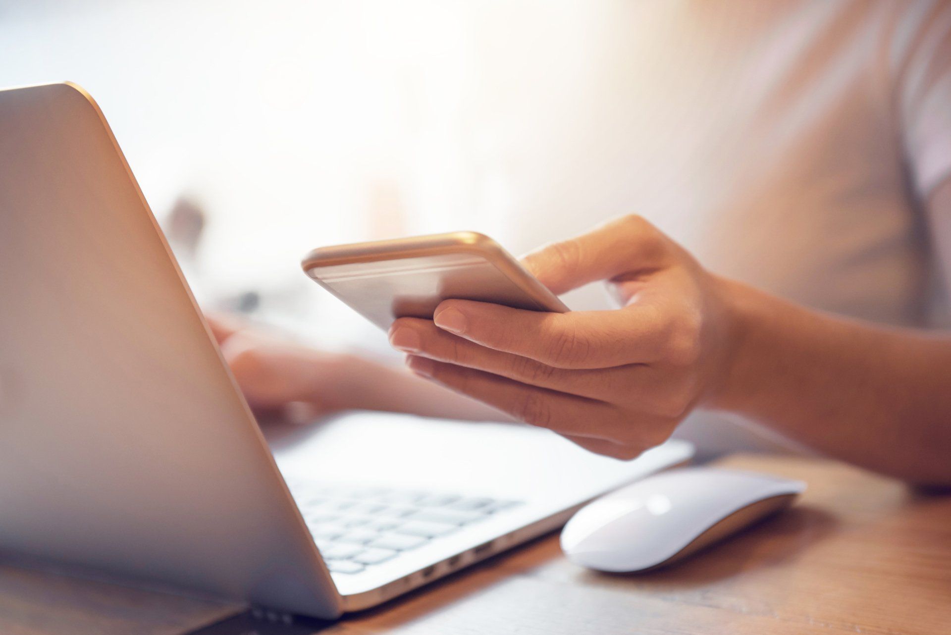 Woman Holding a Phone while Using a Laptop — Merritt Island, FL — Eye Clinic & Laser Institute
