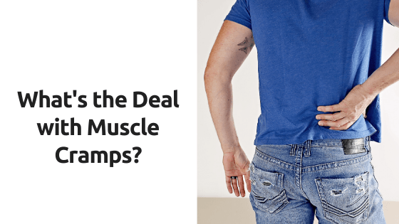 A man in a blue shirt is holding his back in pain.