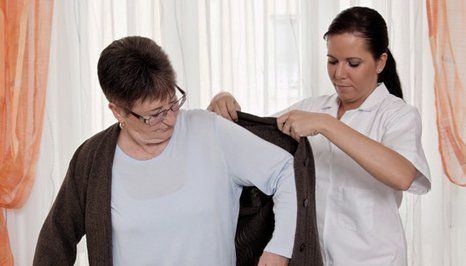 A nurse helping a lady dress