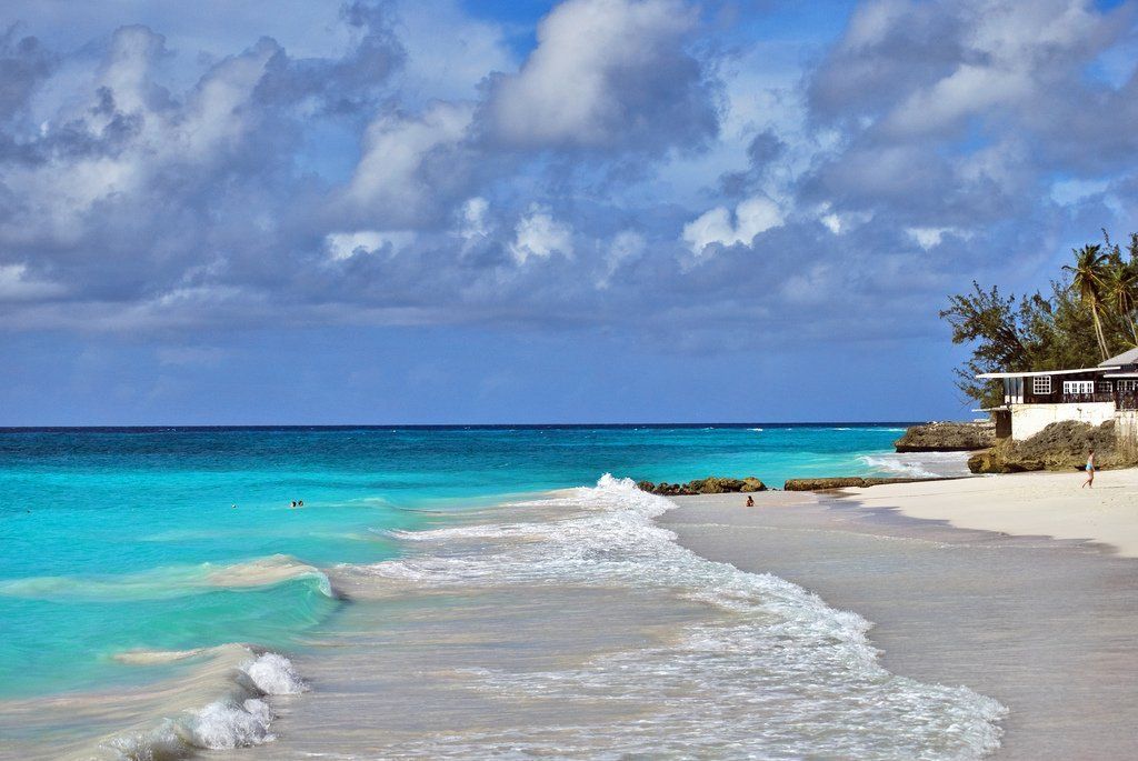 A beach with waves crashing against the shore on a cloudy day.