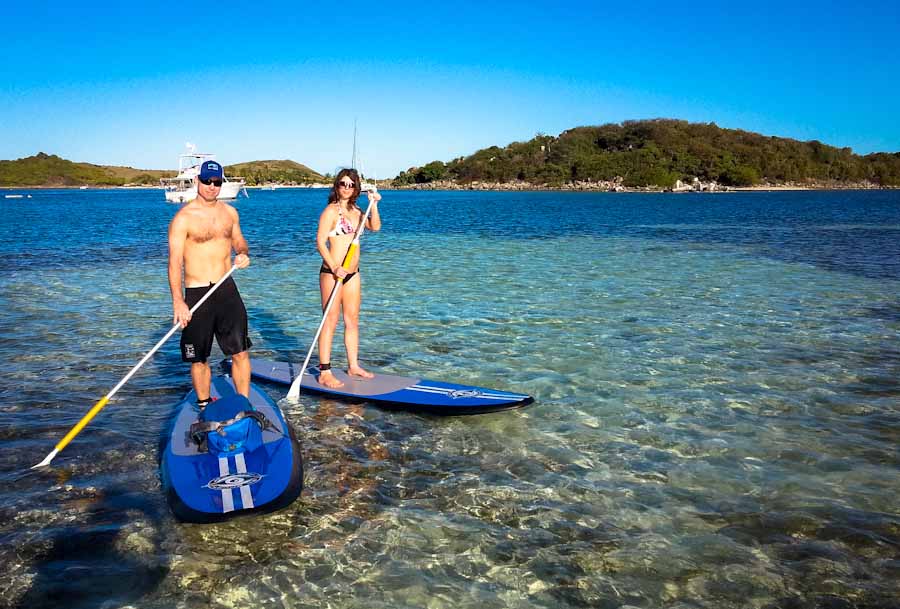 A man and a woman are standing on paddle boards in the water.