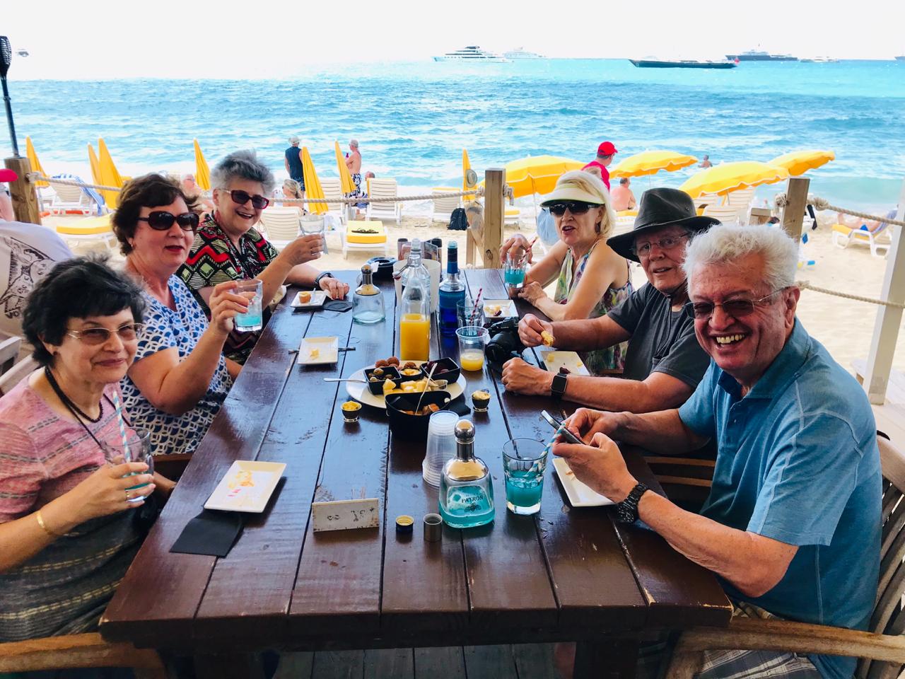A group of people are sitting at a table with a view of the ocean.