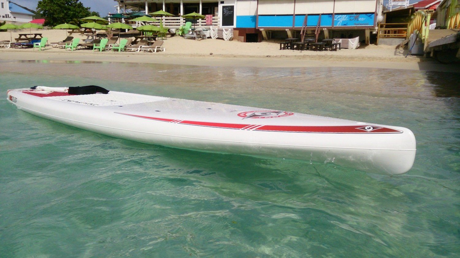 A paddle board is floating in the water near a beach