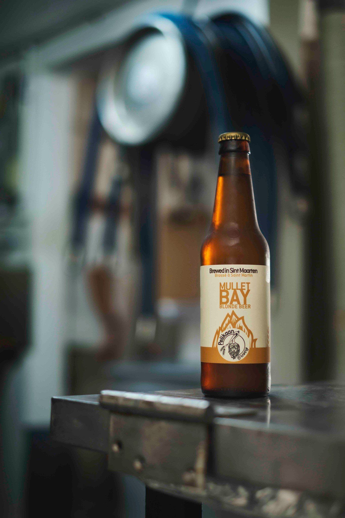 A bottle of beer is sitting on a metal table.