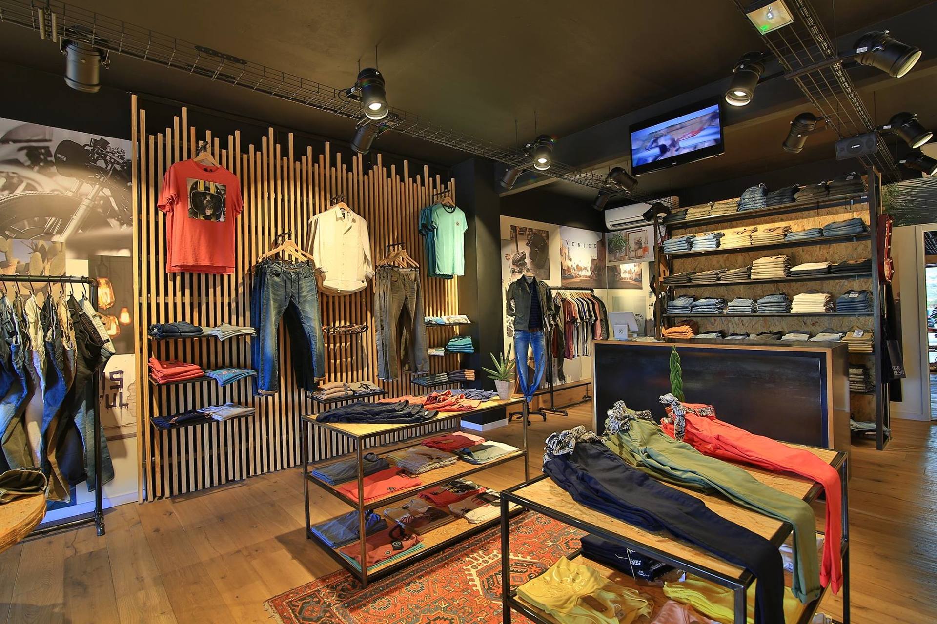 A store filled with clothes and a television on the ceiling.