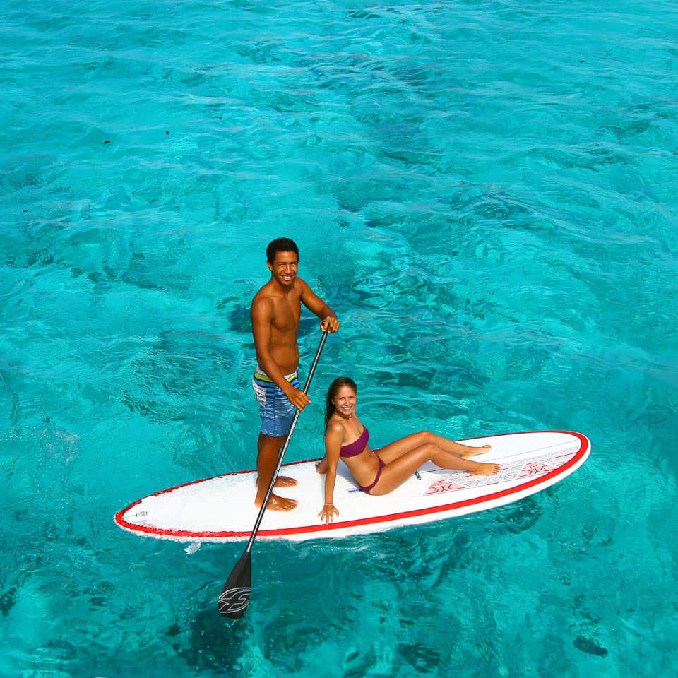A man and a woman are on a paddle board in the ocean