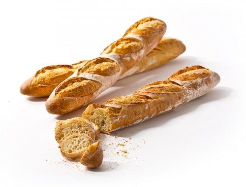 Two baguettes are sitting next to each other on a white surface.