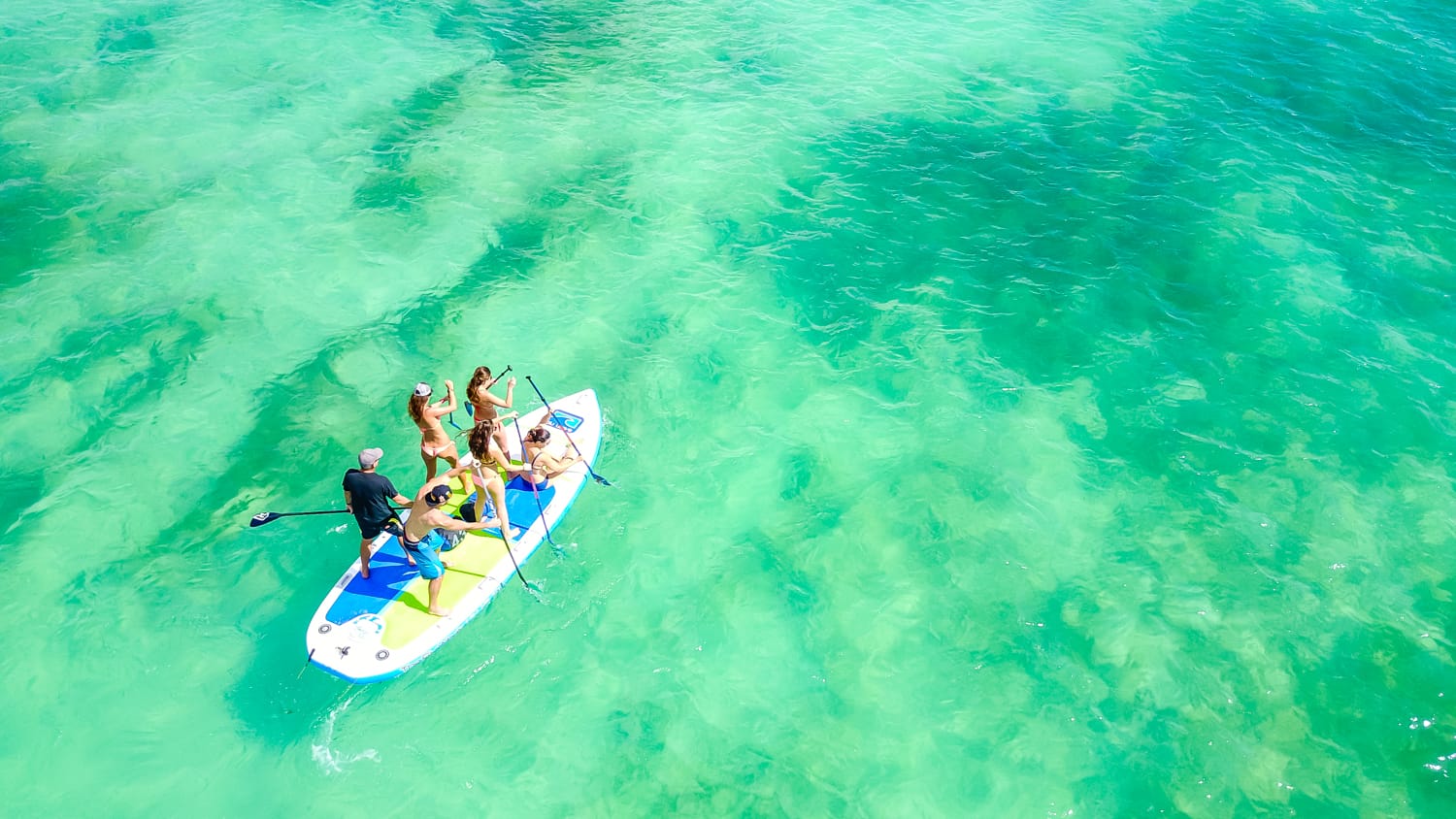 A group of people are riding a paddle board in the ocean.