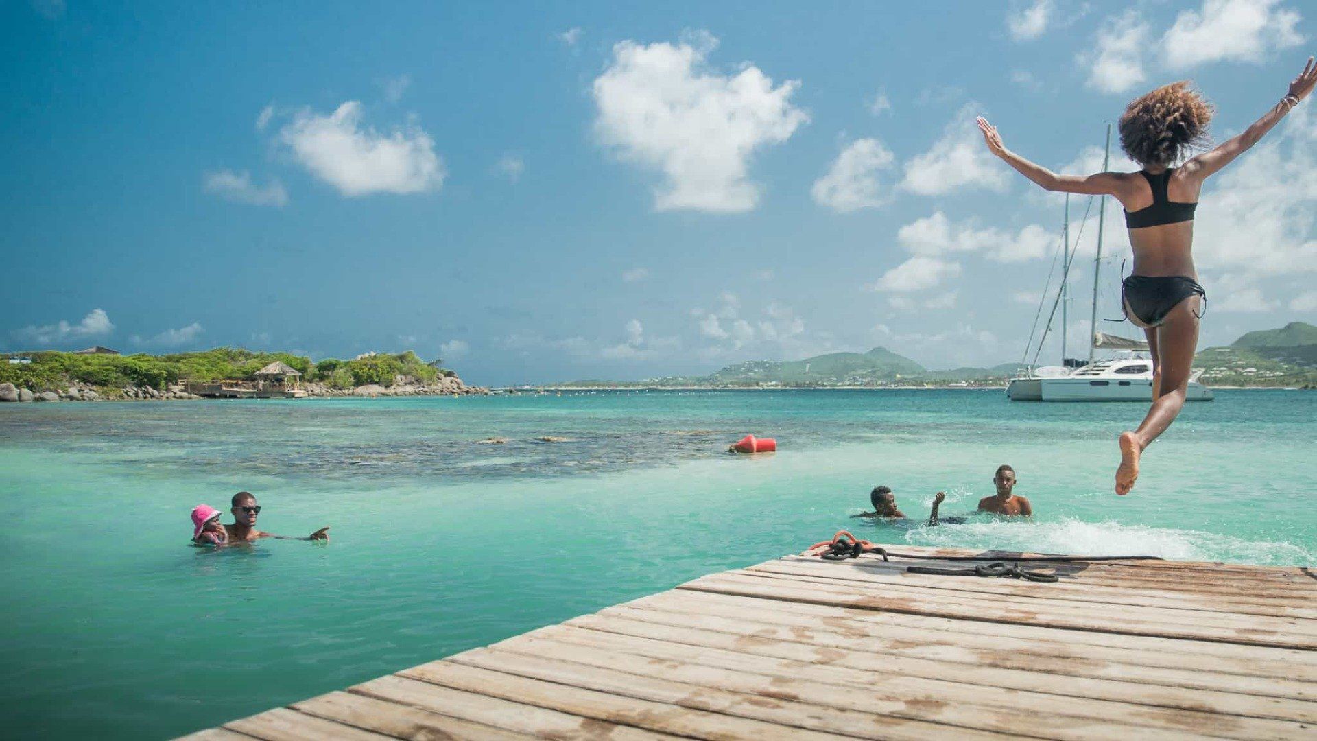Girl Jumping in the water from Yellow Beach restaurant's pier.
