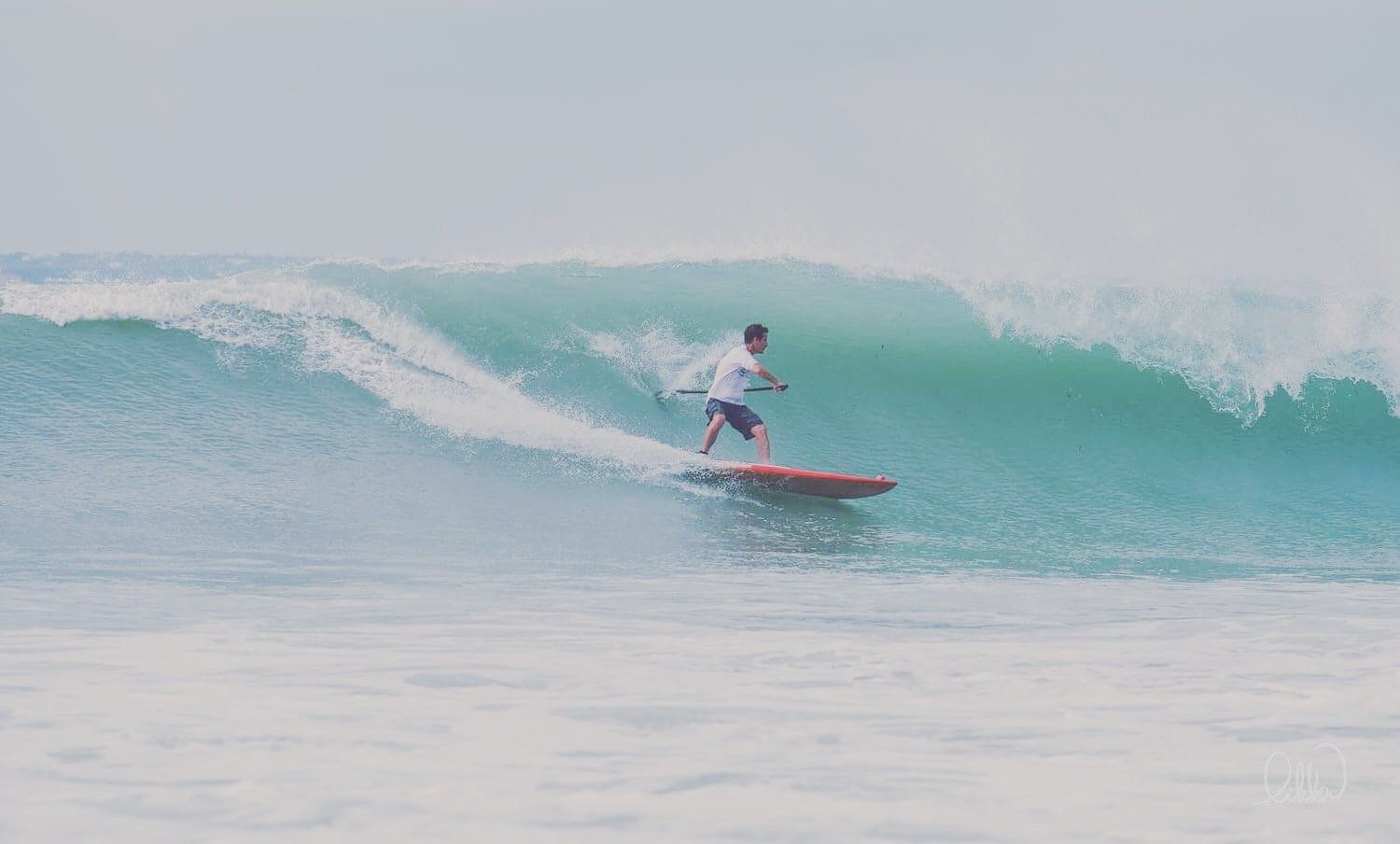 A man is riding a wave on a surfboard in the ocean.