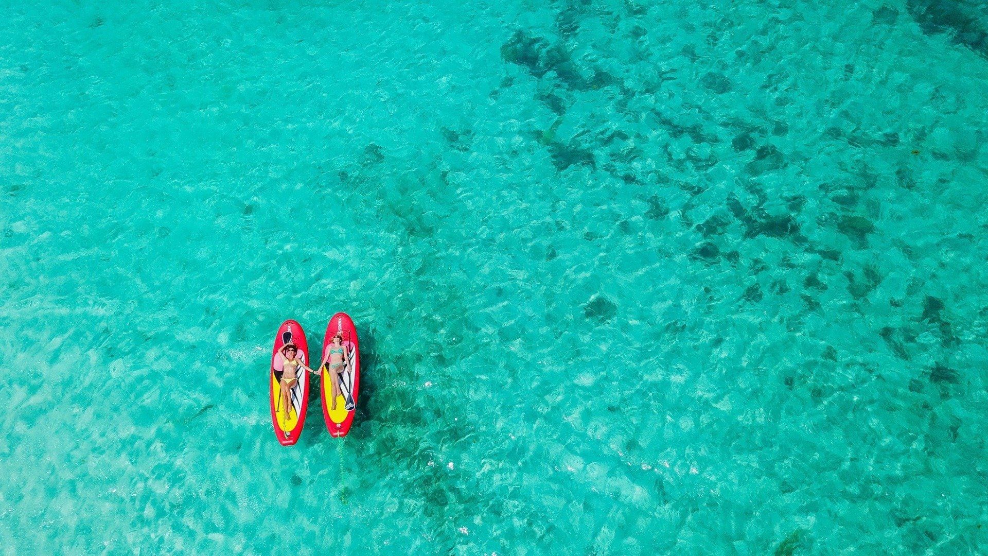 2 girls laying on red paddle boards