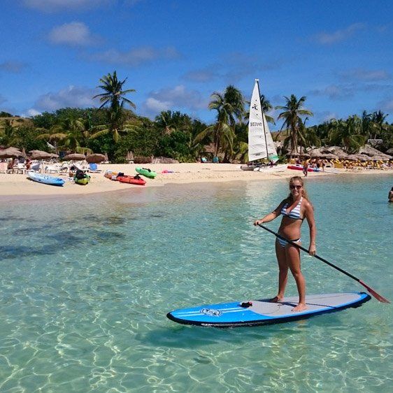 A woman in a bikini is standing on a paddle board in the ocean