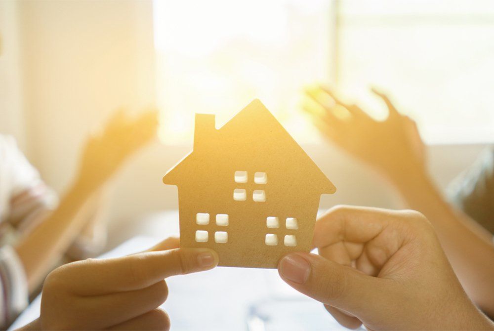 two hands holding wooden model house