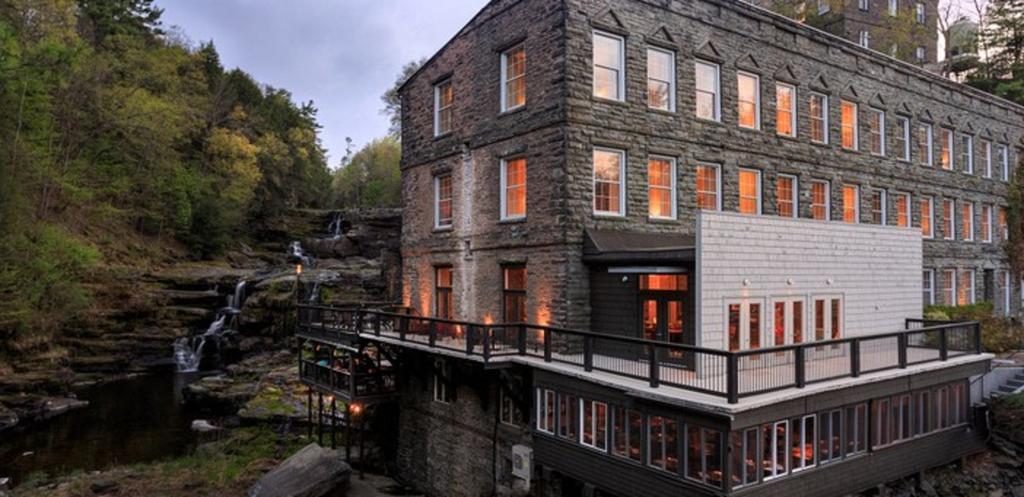 A large building with a lot of windows is surrounded by trees and a river.
