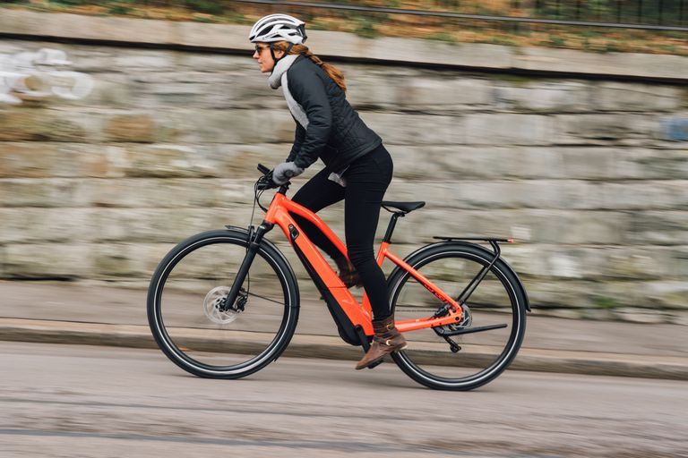 A woman is riding an electric bike down a street.