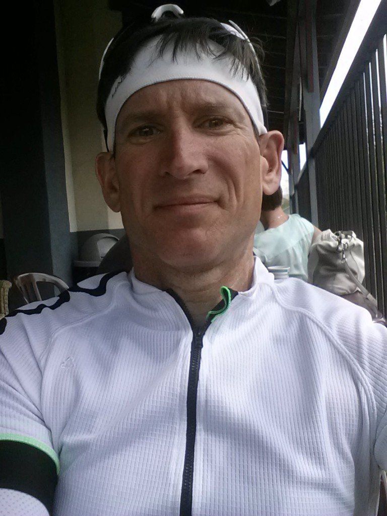 A man wearing a headband and sunglasses is taking a selfie.