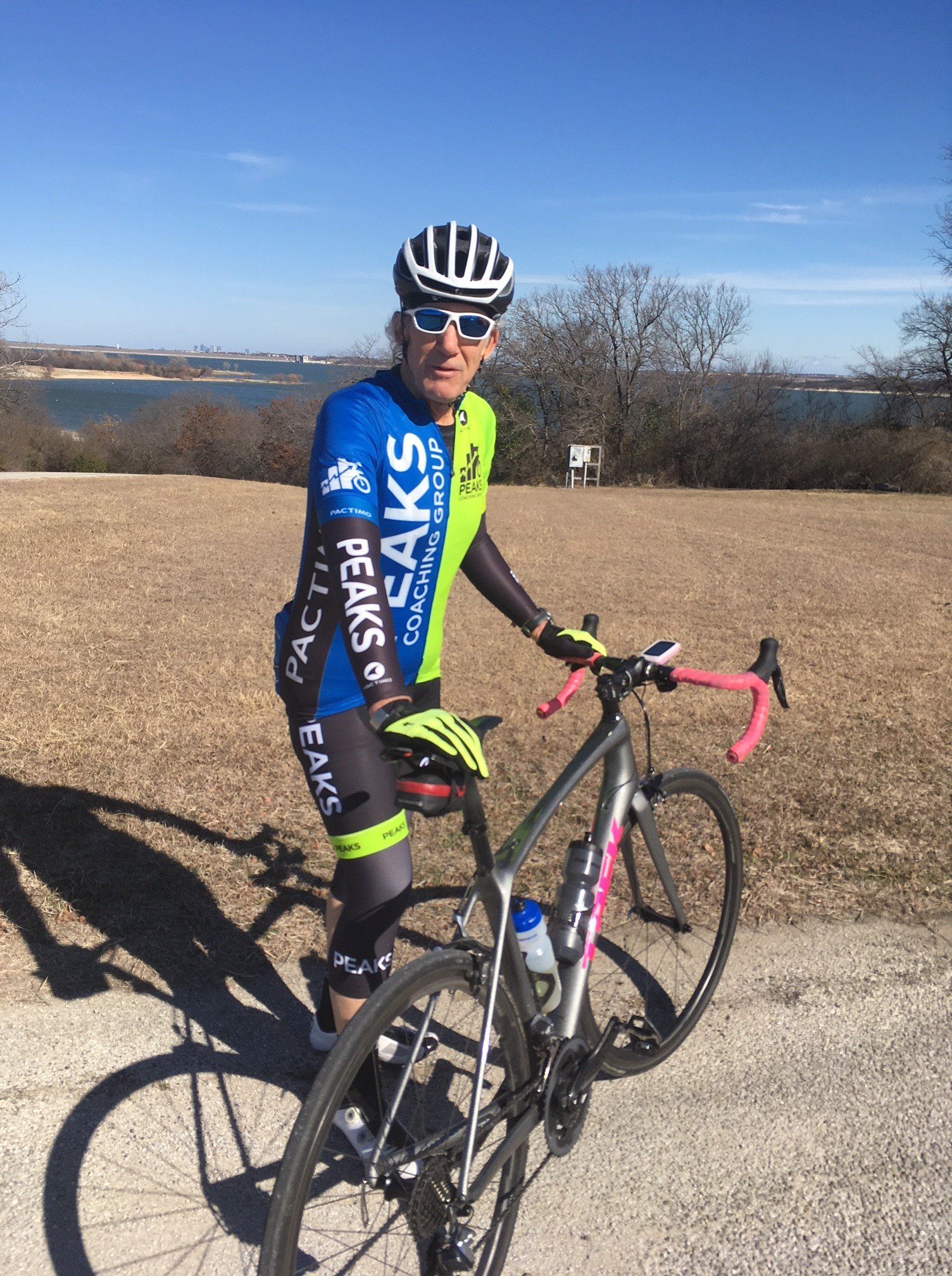 A man is standing next to a bicycle on a dirt road.