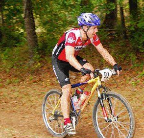 A man wearing a helmet is riding a bike on a dirt road.