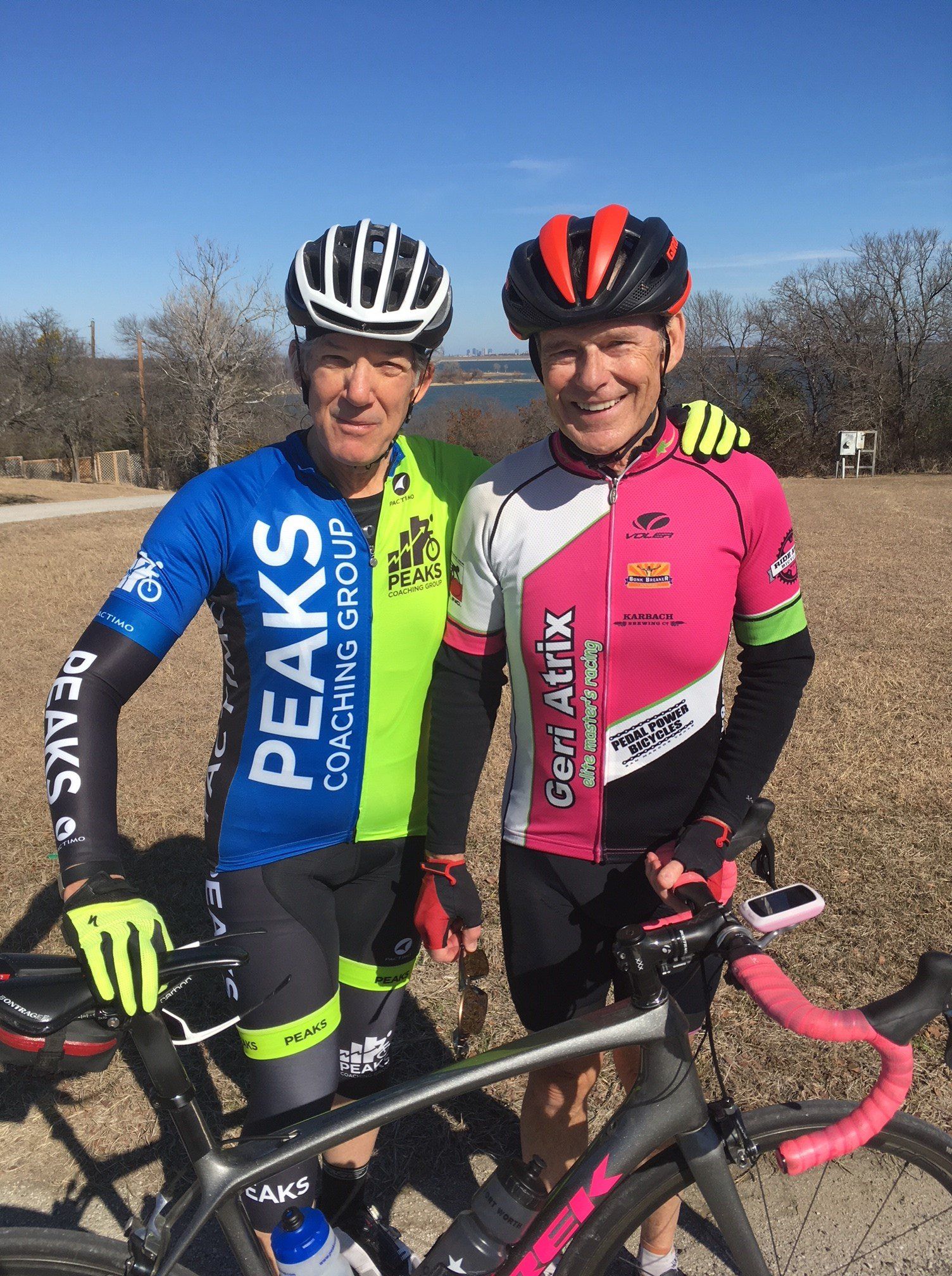 Two men are standing next to each other with bicycles.