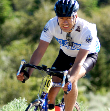 A man wearing a el salvador shirt is riding a bike