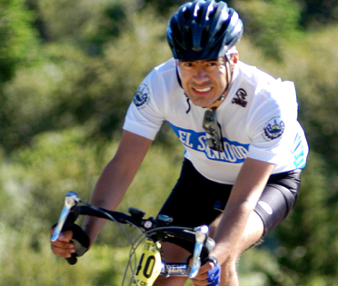 A man wearing a el salvador shirt is riding a bike