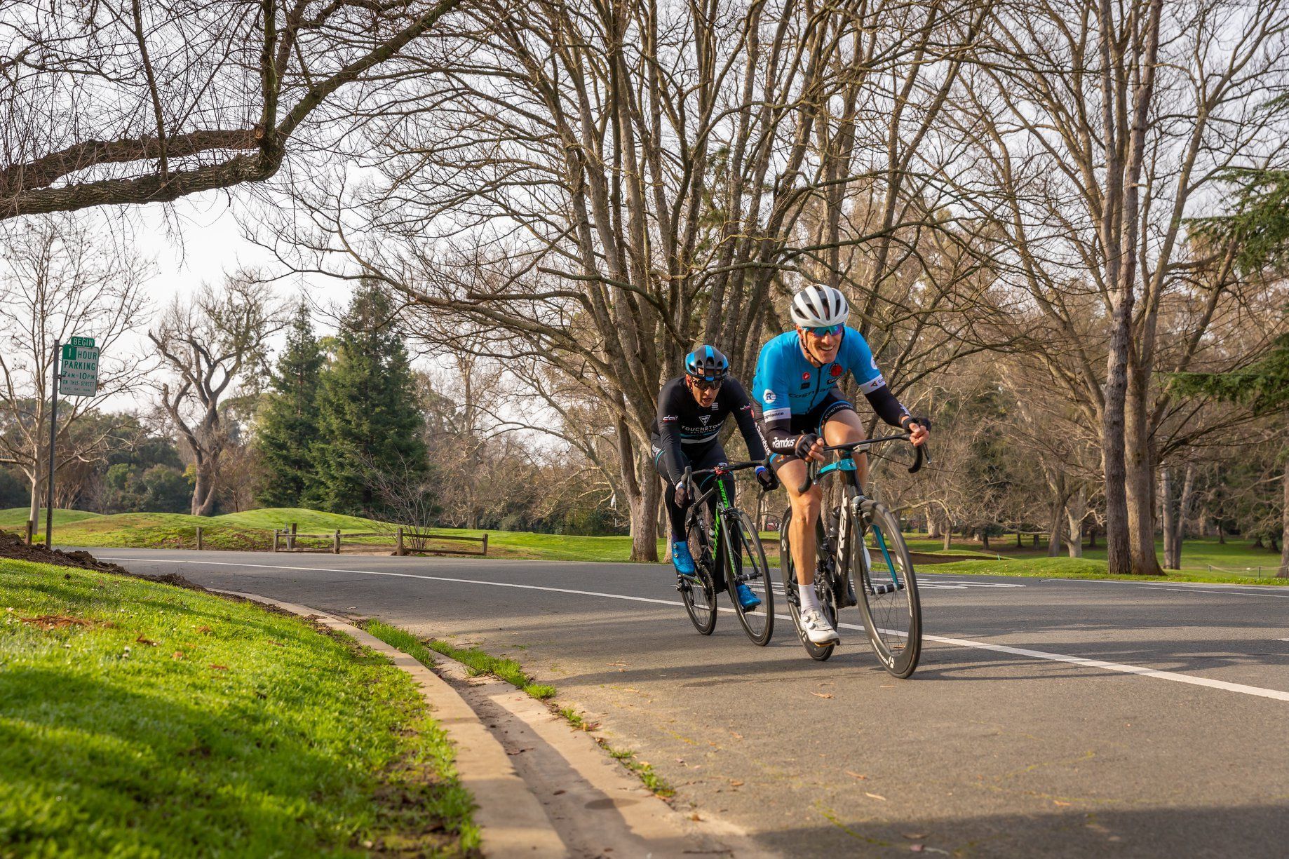 Two people are riding bicycles down a road.