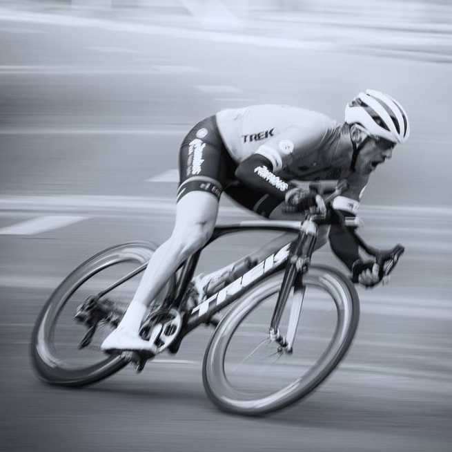 A man wearing a trek jersey is riding a bike