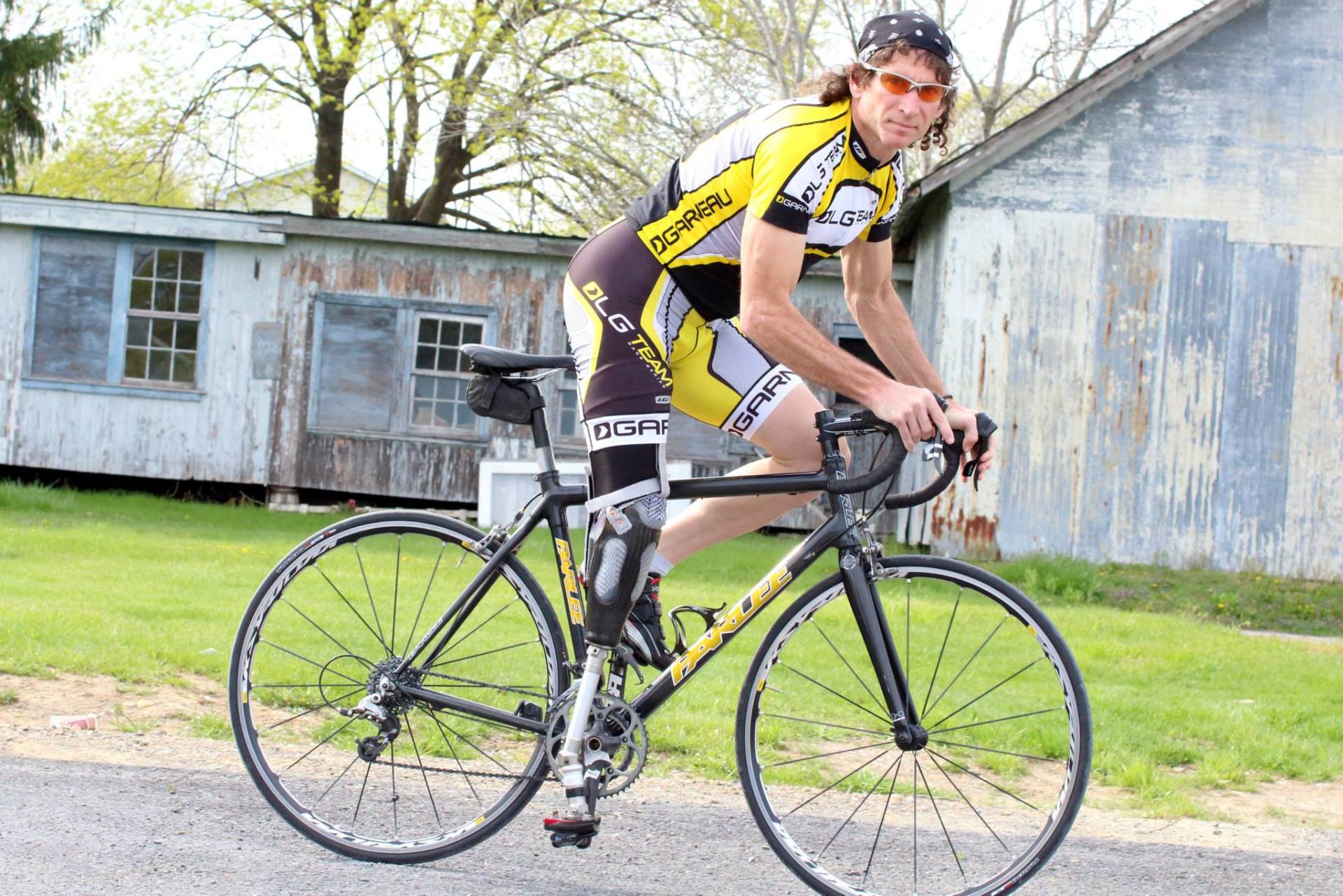 A man is riding a bike on a road in front of a building