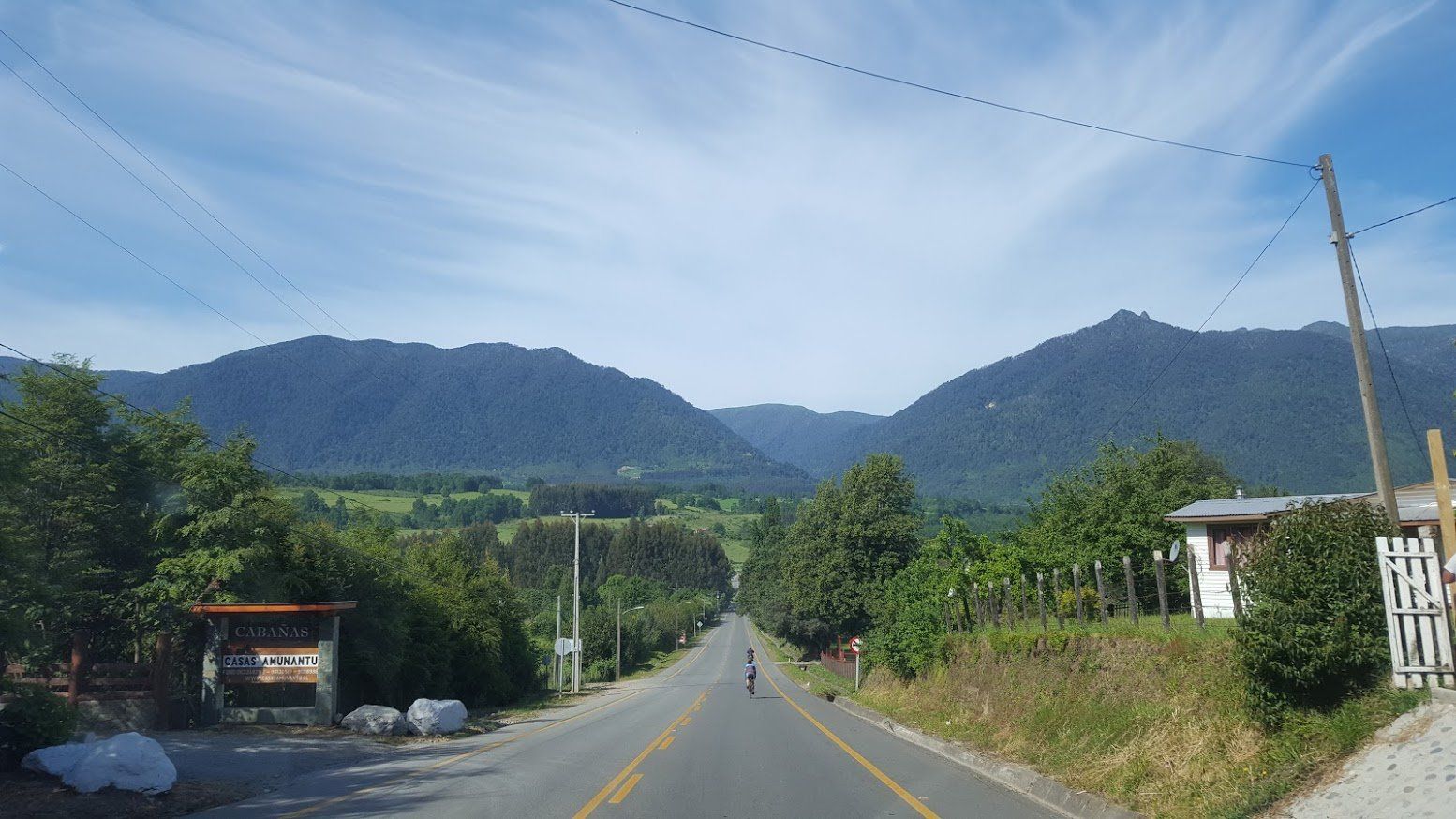 A road with mountains in the background and trees on the side