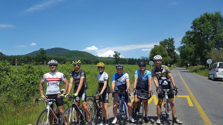 A group of cyclists are standing next to each other on the side of a road.