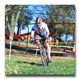 A man wearing a helmet is riding a bike down a grassy hill