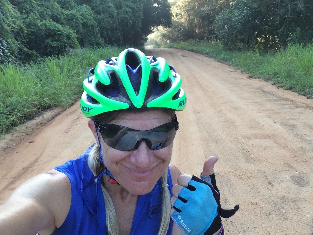 A woman wearing a helmet and sunglasses is giving a thumbs up