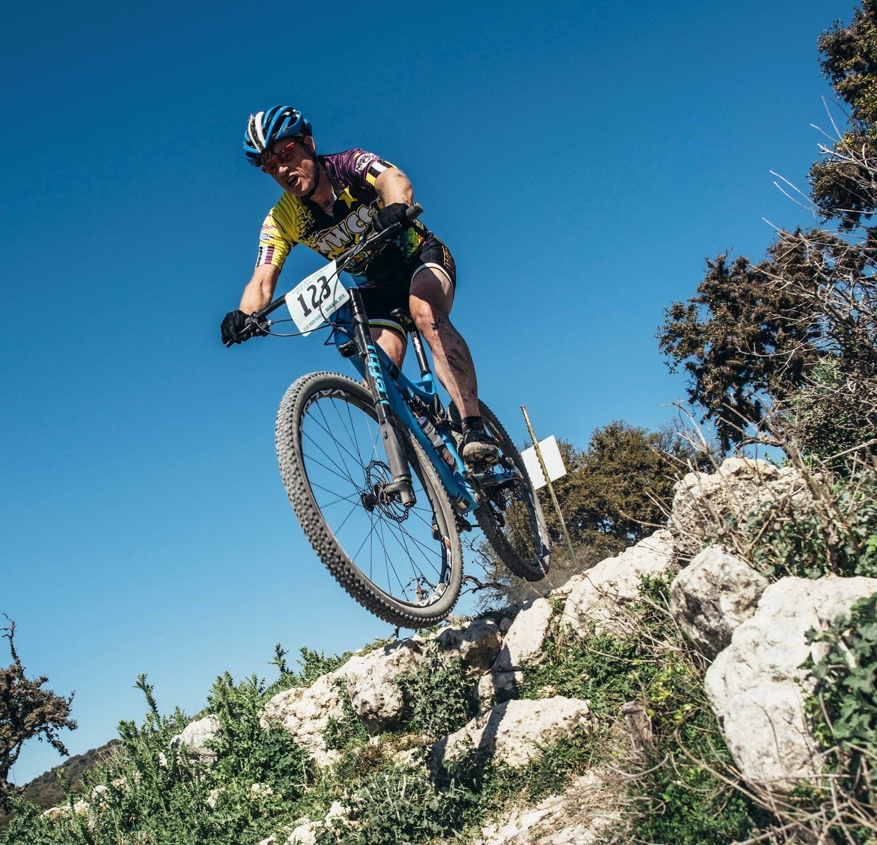 A man is riding a bike down a rocky hill.