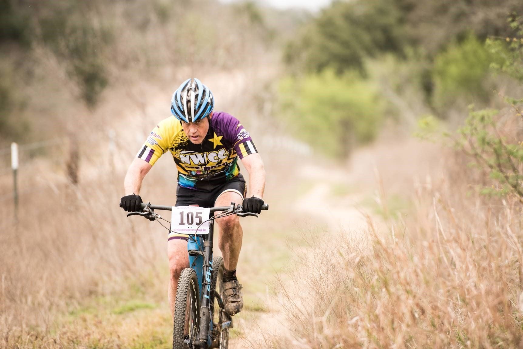 A man is riding a bike on a dirt road.