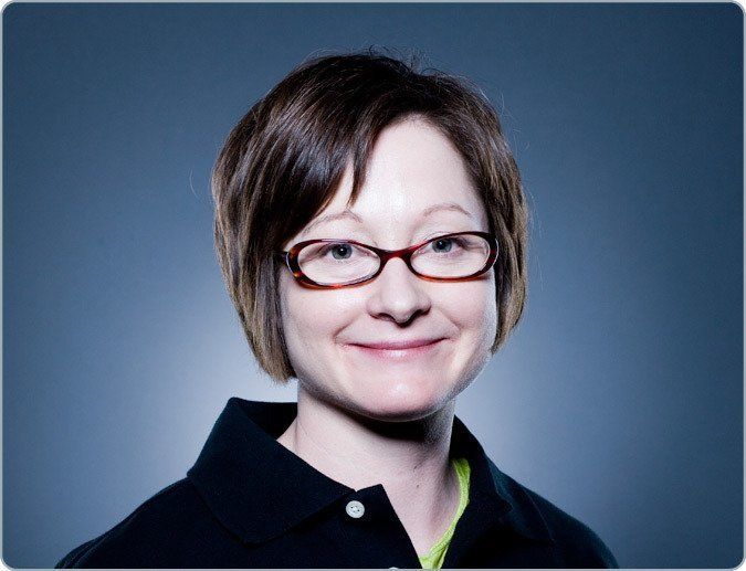 A woman wearing glasses and a black shirt smiles for the camera
