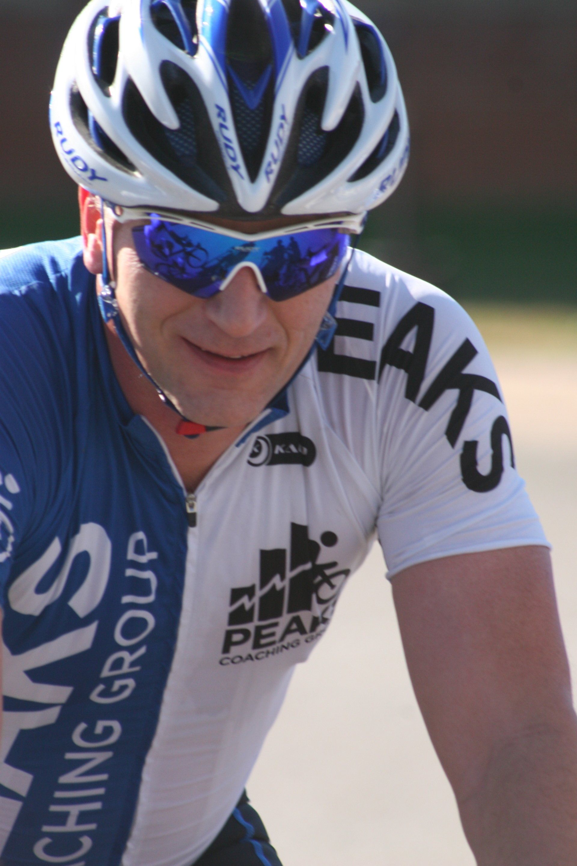A man wearing a helmet and sunglasses has the word peak on his shirt
