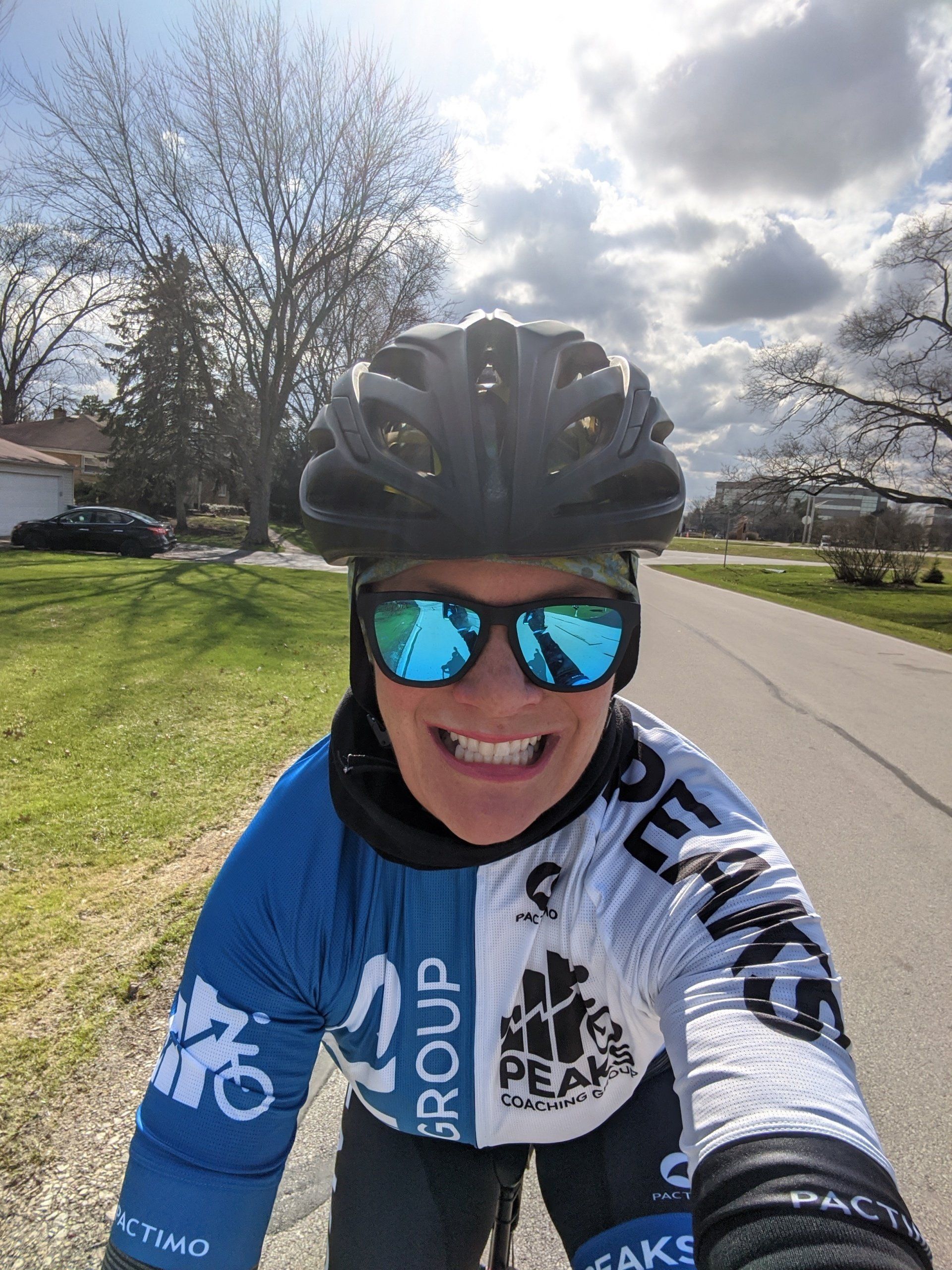 A woman wearing a helmet and sunglasses is taking a selfie while riding a bike.