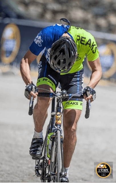 A man is riding a bike with the word peaks on his jersey