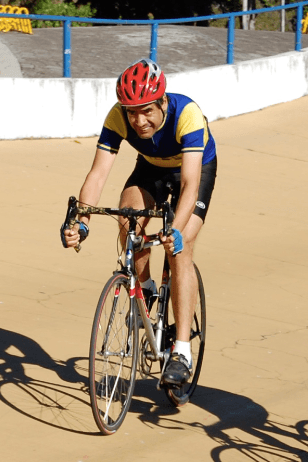 A man wearing a red helmet is riding a bike