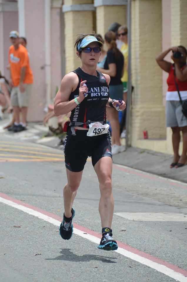 A woman is running down a street in a triathlon.