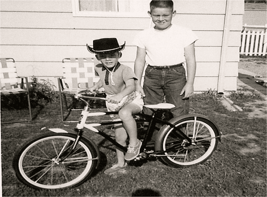 A boy in a cowboy hat sits next to a girl on a bike