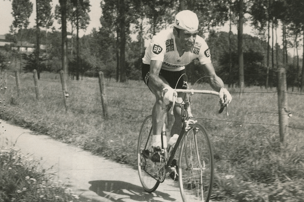 A man is riding a bicycle down a dirt road.