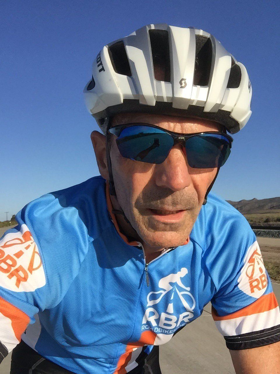A man wearing a helmet and sunglasses is riding a bike
