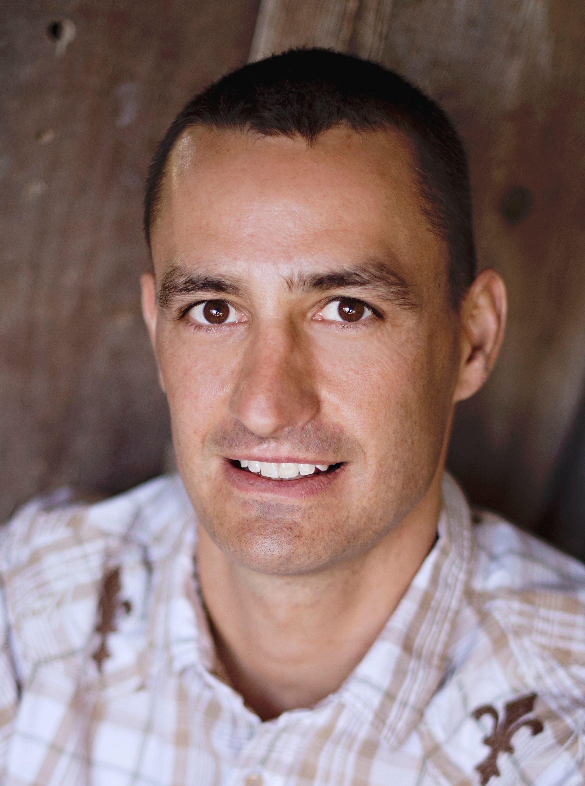 A man in a plaid shirt is smiling for the camera.