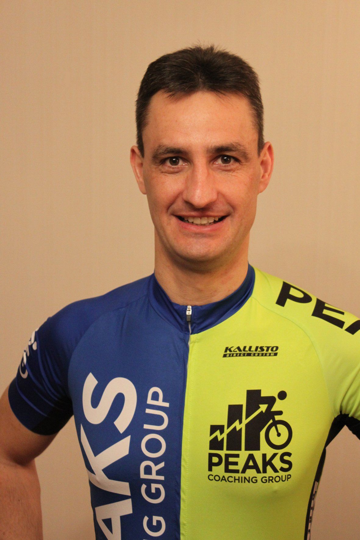 A man wearing a blue and yellow peaks cycling jersey