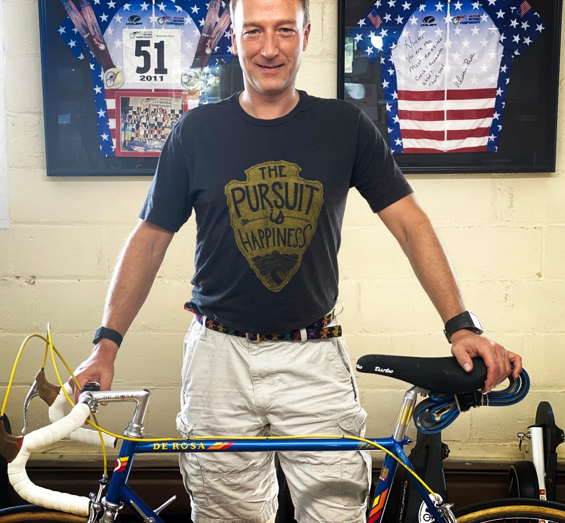 A man wearing a shirt that says the pursuit of happiness