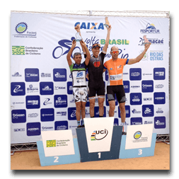 Three athletes are standing on a podium with the word caixa behind them