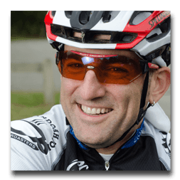 A man wearing a helmet and sunglasses is smiling