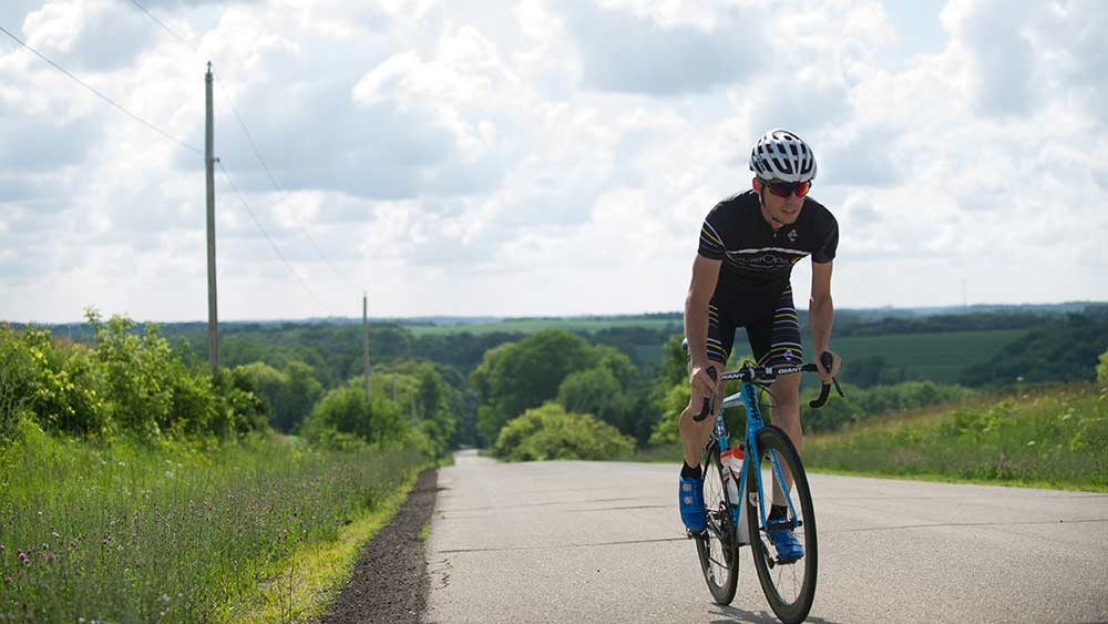 A man is riding a bike down a country road.